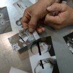 Close-up of handcuffed person examining crime scene photos on table, indicating investigation process.